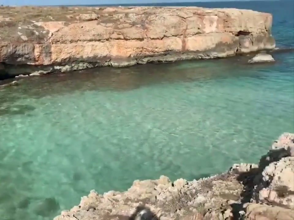 Clear turquoise water beneath pale limestone cliffs on the Puglia coast
