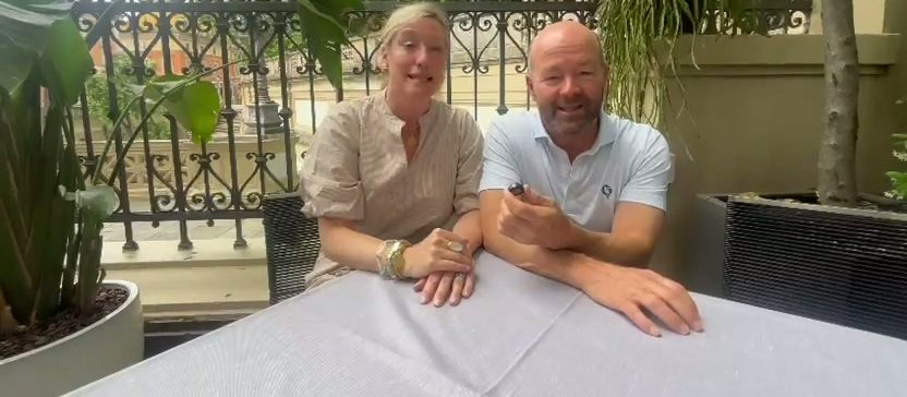Una pareja de clientes sonríe en una mesa de terraza