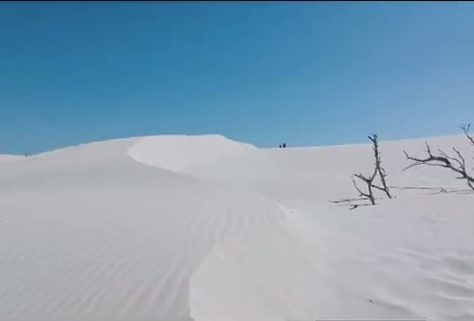 White Sardinian sand dunes with rippled sand beneath a clear blue sky