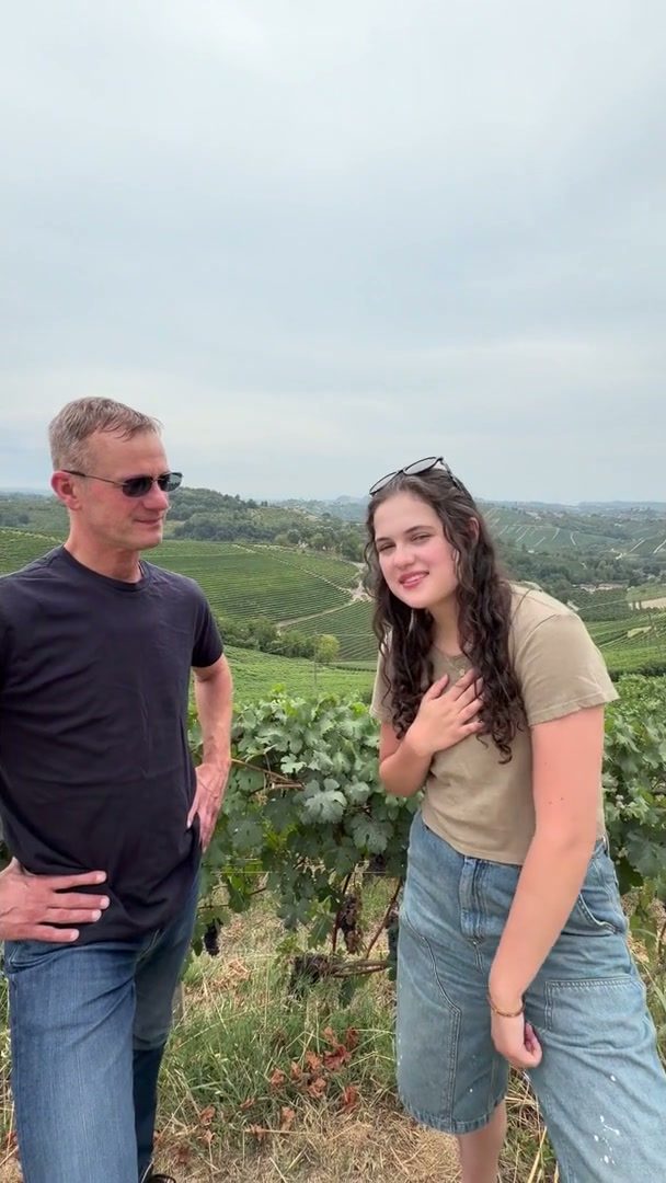 Two clients smiling among vineyards with rolling hills behind them