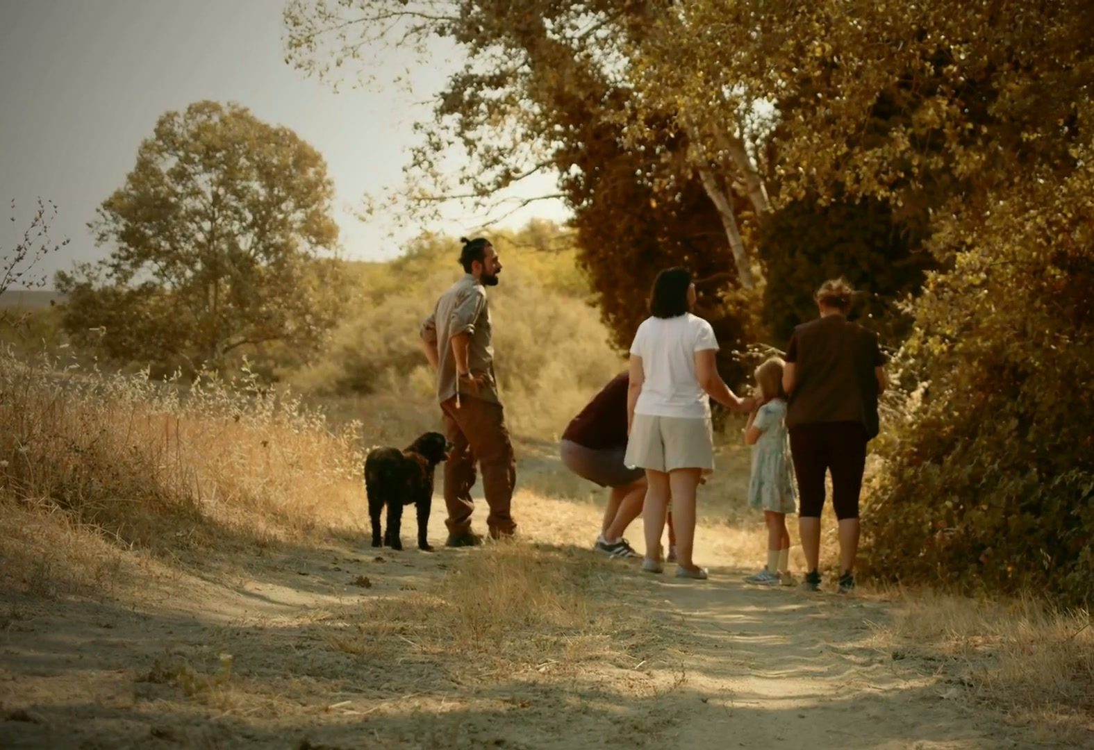Truffle hunter and guests with a dog on a sunlit Tuscan country path