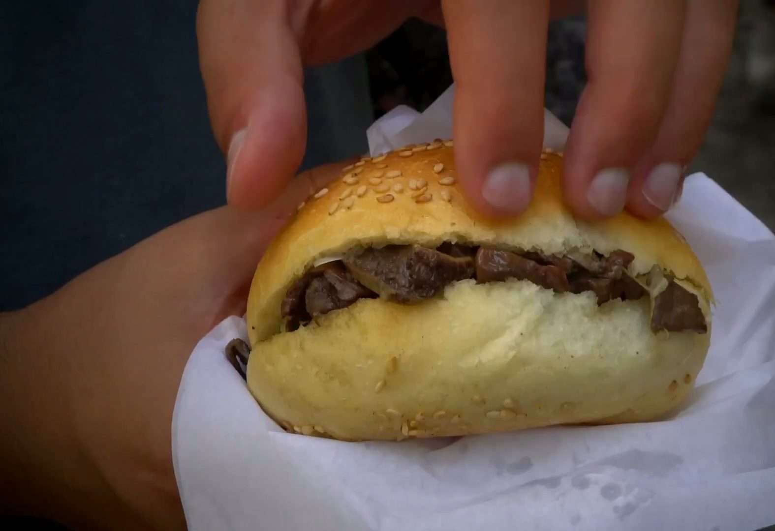 Close-up of a traditional Sicilian street-food sandwich held in a paper wrapper