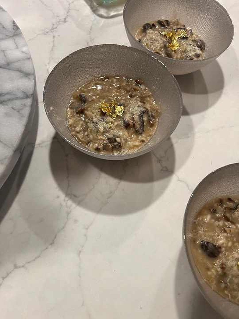 Ciotole di risotto con una guarnizione dorata su un piano da cucina in marmo