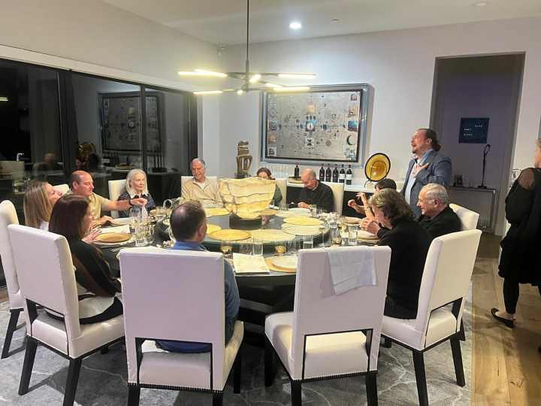 Guests gathered around a round dining table with our chef standing beside them