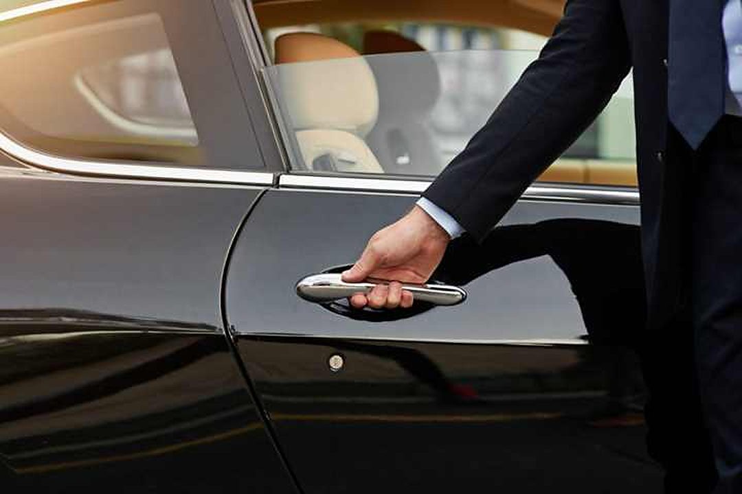 La mano di un autista che apre la portiera di un'auto nera